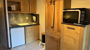 Une cuisine compacte avec des meubles en bois, un four à micro-ondes, un réfrigérateur et un petit évier.