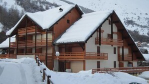 Un bâtiment de style chalet, doté de nombreux balcons et entouré de montagnes enneigées.