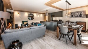 Un salon moderne avec un canapé gris, une table à manger dressée pour six personnes et un coin cuisine doté d’un îlot central.
