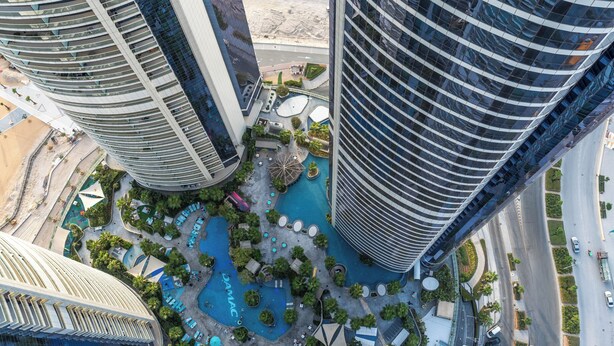 A high-rise building with a rooftop pool and surrounding greenery.