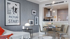 A modern living room with a sofa, coffee table, and a dining area with a table and chairs.