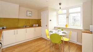 Una cocina con una mesa de comedor para dos personas, una ventana con vistas y un reloj en la pared.
