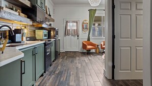 A compact kitchen with modern appliances and a dining area with a chair and table. - Walk to town and beach (Ocean Springs)