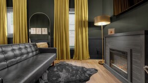 A modern living room with a black leather sofa, a black rug, a floor lamp, and a fireplace. - Walk to town and beach (Ocean Springs)