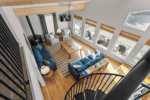 A modern living room with a staircase, large windows, and a fireplace.