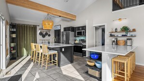 Una cocina moderna con una isla central, taburetes de bar y un comedor.