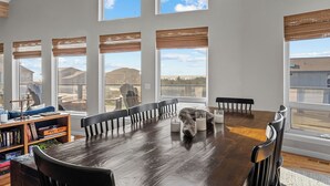 Un comedor amplio con una larga mesa de madera, numerosas sillas y grandes ventanales que ofrecen vistas del paisaje circundante.
