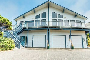 En toetages bygning med balkon, trappe og to garageporte.