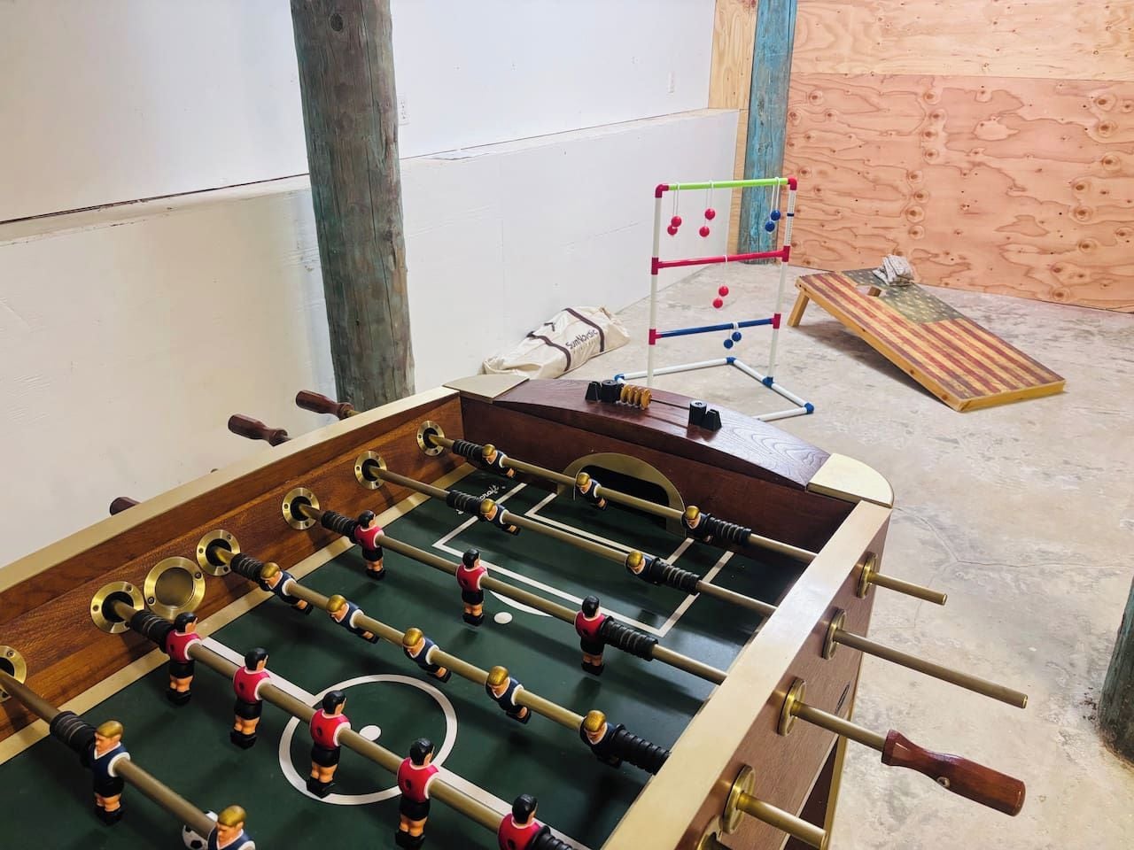 A foosball table with multiple players and a small table tennis table in the background.