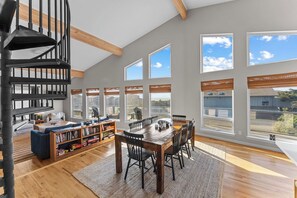 A spacious room with a wooden dining table, a built-in bookshelf, and a spiral staircase.