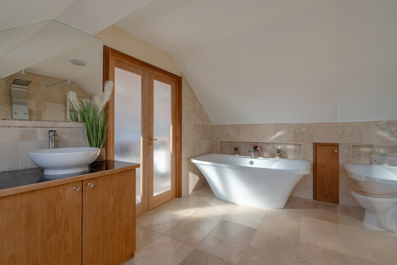 Ein modernes Badezimmer mit freistehender Badewanne, einem Doppelwaschtisch und einem großen Spiegel.