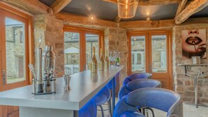 Eine rustikale Bar mit einer Steinwand, Holzbalken und einer Theke mit Barhocker.