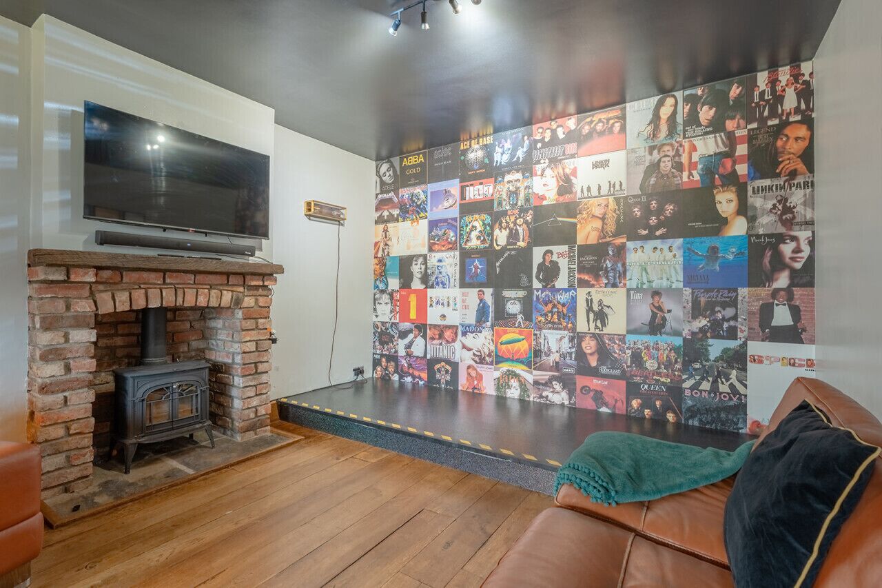 Ein Wohnzimmer mit Kamin aus Ziegelsteinen, einem Flachbildfernseher und einer Wand voller Filmplakate.