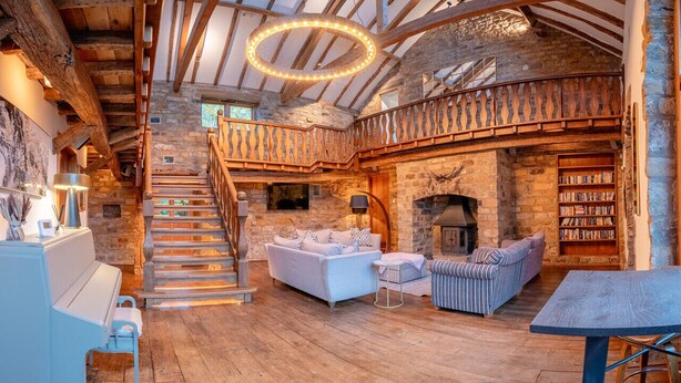 Ein rustikales Interieur mit einer Holztreppe, einem Kamin und einer gemütlichen Sitzecke.