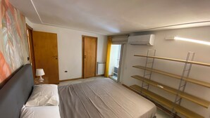 A bedroom with a bed, a nightstand, a wall-mounted shelf, and an air conditioning unit. - Dimora Tribunali 236, main street, 300 mt from metro (Napoli)