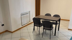 A small, clean room with a wooden table, four chairs, a blue sofa, and a radiator. - Dimora Tribunali 236, main street, 300 mt from metro (Napoli)