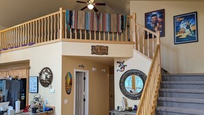 A spacious kitchen with a refrigerator, sink, and countertop. A wooden staircase leads to a loft area with a ceiling fan. - HIDDEN SPACIOUS 4-bdr RETREAT FOR FAMILIES AND FRIENDS!  (Show Low)