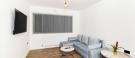 A modern living room with a grey sofa, a round coffee table, and a small side table.