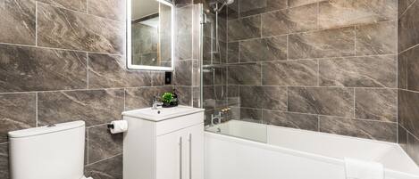 A modern bathroom with a toilet, sink, and bathtub.