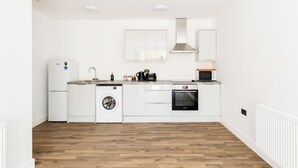 Una cocina moderna con armarios blancos, lavadora integrada, microondas y estufa.
