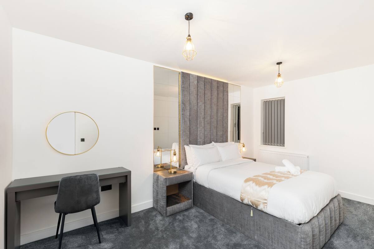 Une chambre à coucher moderne avec un lit, une table de chevet, une chaise et un grand miroir.