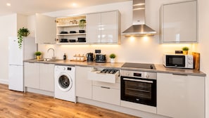 Una cocina moderna con armarios blancos, lavadora integrada, microondas y estufa.