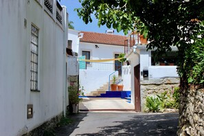 Eine enge Straße mit einer Treppe, die zu einem Gebäude mit blauer Brüstung und weißer Fassade führt.