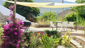 Eine Terrassengruppe mit Tisch und Stühlen, umgeben von Pflanzen und Blick auf die Hügel.