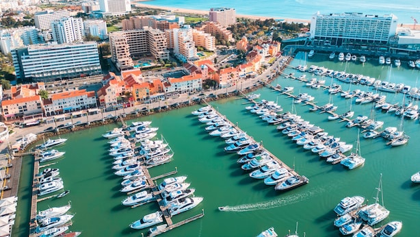 A marina with numerous boats docked, surrounded by buildings and a clear view of the sea. - Apartment Portofino 1 (Loulé)