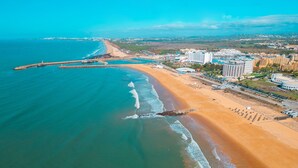 An aerial view of a coastal area with a sandy beach, a marina, and a cityscape in the background. - Apartment Portofino 1 (Loulé)