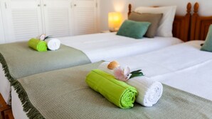 A hotel room with two beds, each with a green towel and a flower. - Apartment Portofino 1 (Loulé)