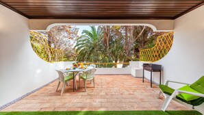 A patio with a table and chairs, surrounded by a yellow fence and trees. - Apartment Portofino 1 (Loulé)