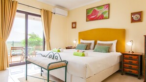 A bedroom with a bed, bedside tables, a chair, and a window with curtains. - Villa Thai (Albufeira)