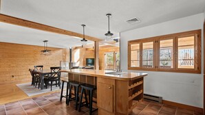 A modern kitchen with a wooden island, bar stools, and pendant lighting.