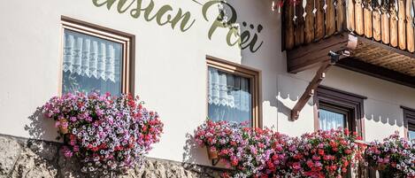 A building with the sign "Pension Plei" and flower boxes on the windows.
