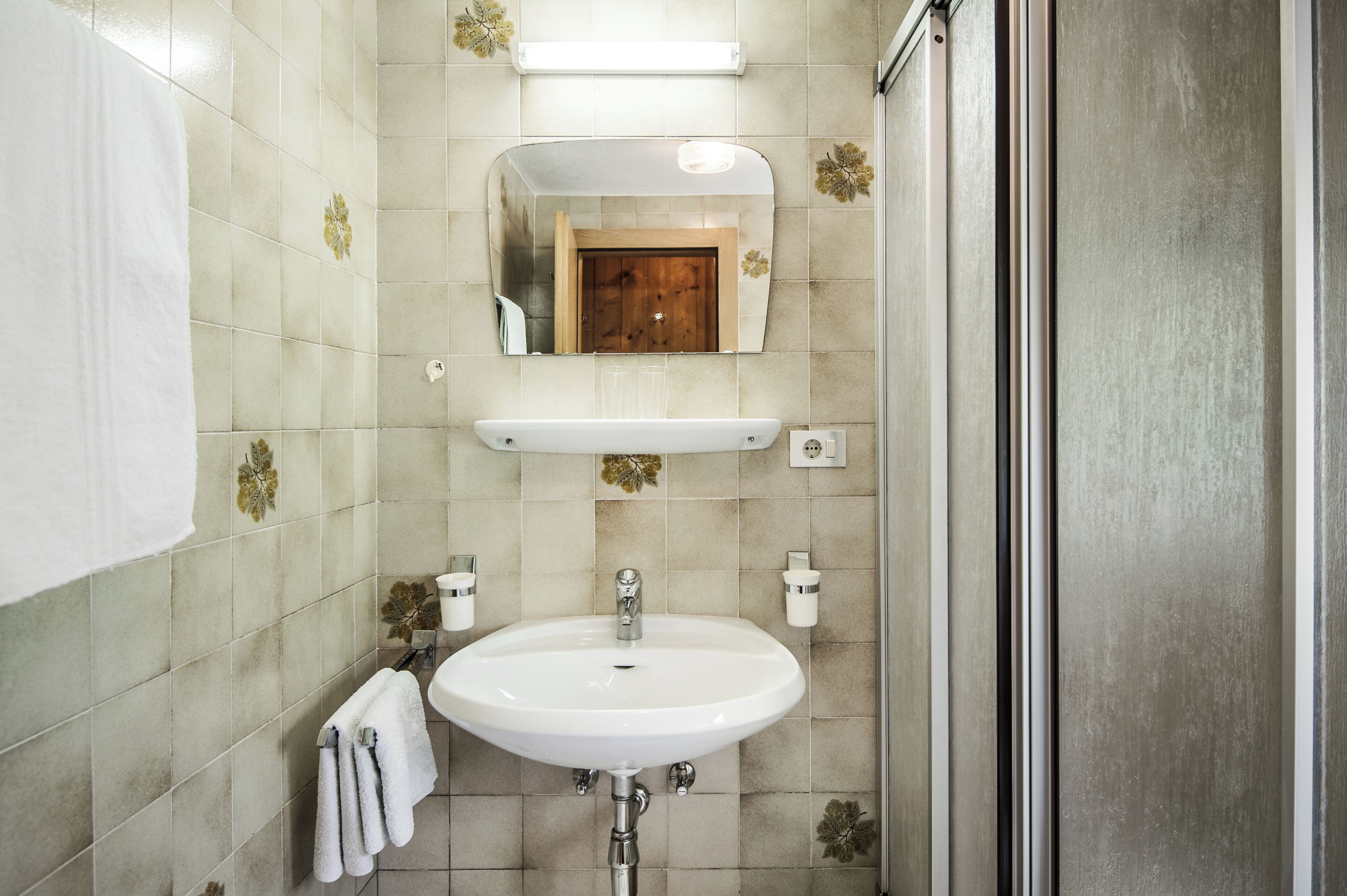 A bathroom with a white sink, a mirror, and a shower area.