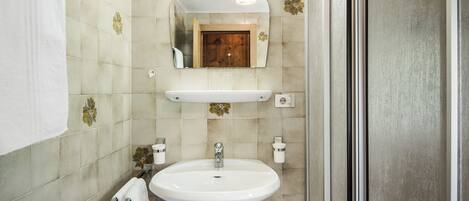 A bathroom with a white sink, a mirror, and a shower area.