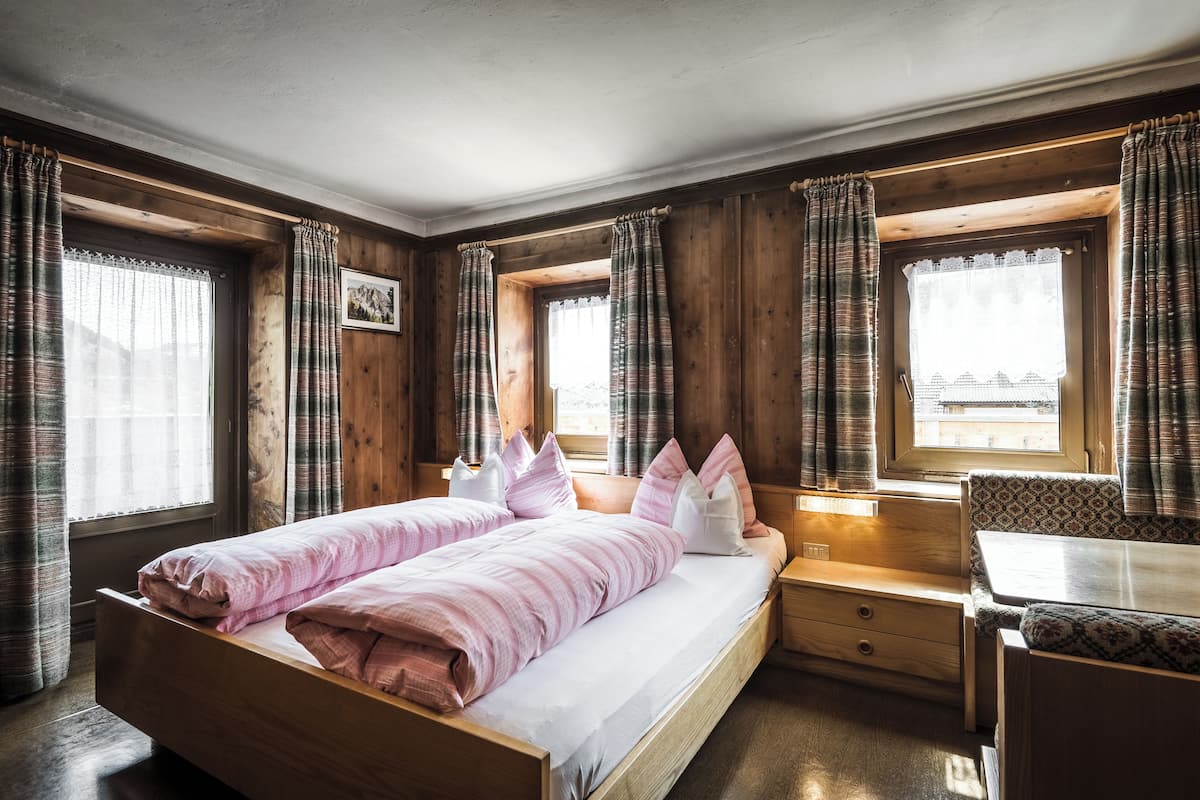 A cozy bedroom with a bed, bedside tables, and a window with curtains.