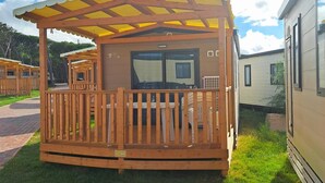 Ein Holz-Wohnmobil mit überdachter Veranda und einem eingezäunten Deckbereich.