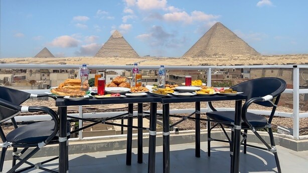 A table set with food and drinks on a balcony with a view of the pyramids. -  Pyramids Express View Inn  (Giza)