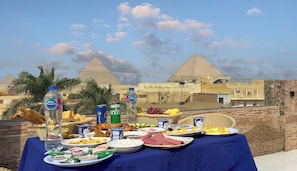 A table set with various food items and drinks, with the pyramids in the background.