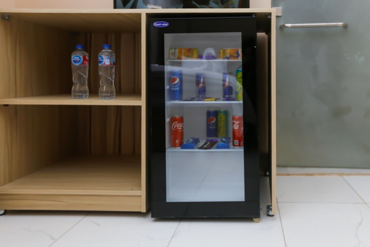 A compact refrigerator with a glass door, containing various beverages and snacks.