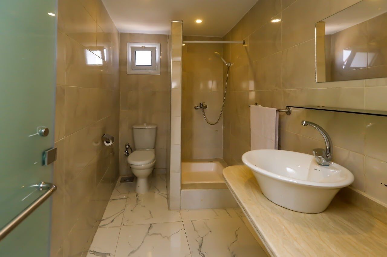 A modern bathroom with a walk-in shower, a toilet, a sink, and a glass-enclosed vanity.
