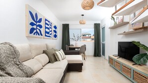 A modern living room with a sofa, a dining table, and a TV.
