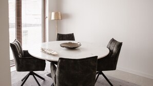 Een ronde eettafel met zes stoelen, een schaal en een lamp.