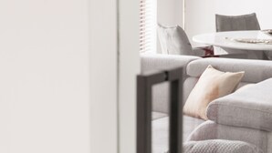 Een moderne woonkamer met een grijze bank, een tafel en een lamp.