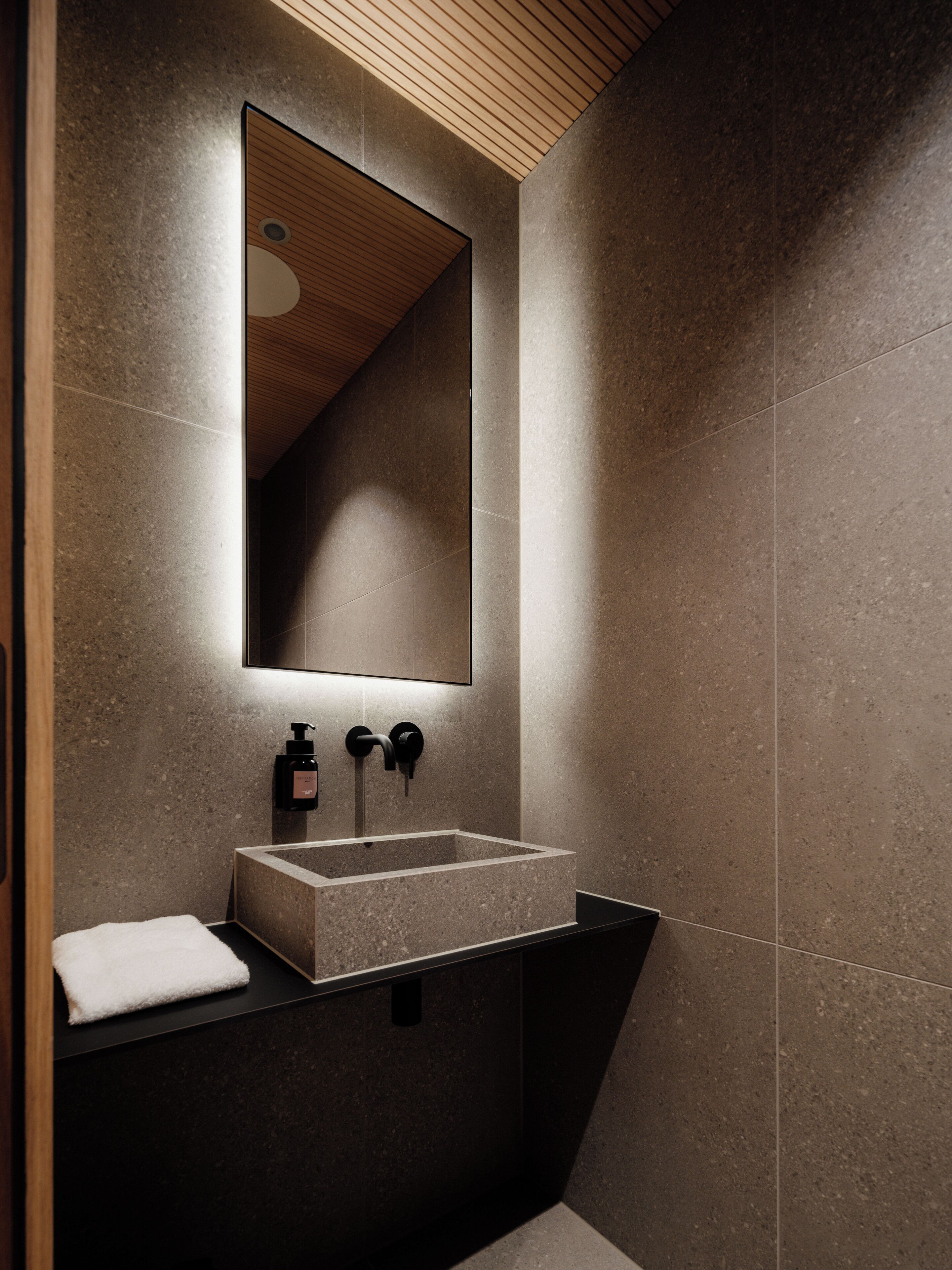A modern bathroom with a rectangular sink, a mirror, and a towel.