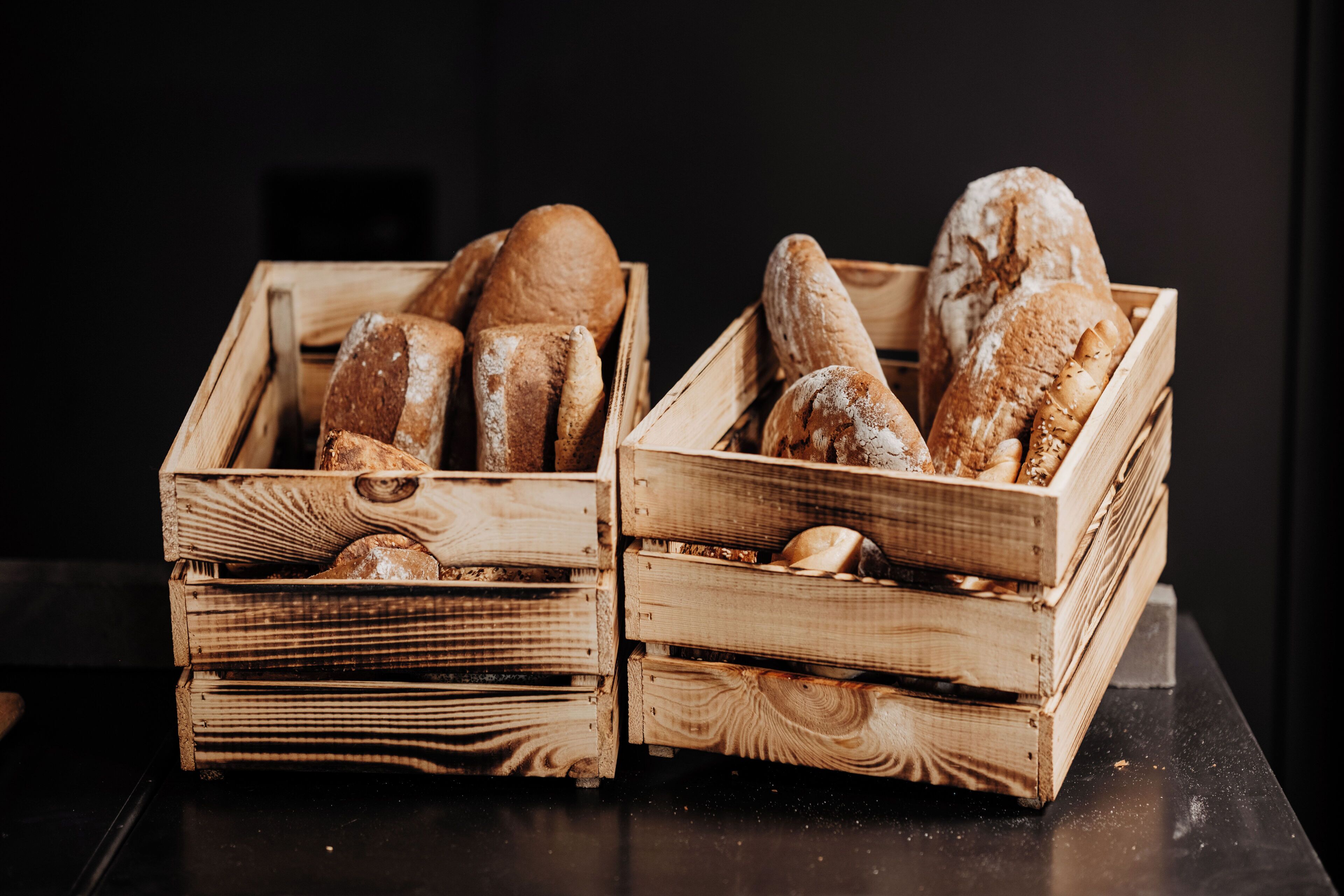 Dos cajas de madera llenas de diferentes tipos de pan.