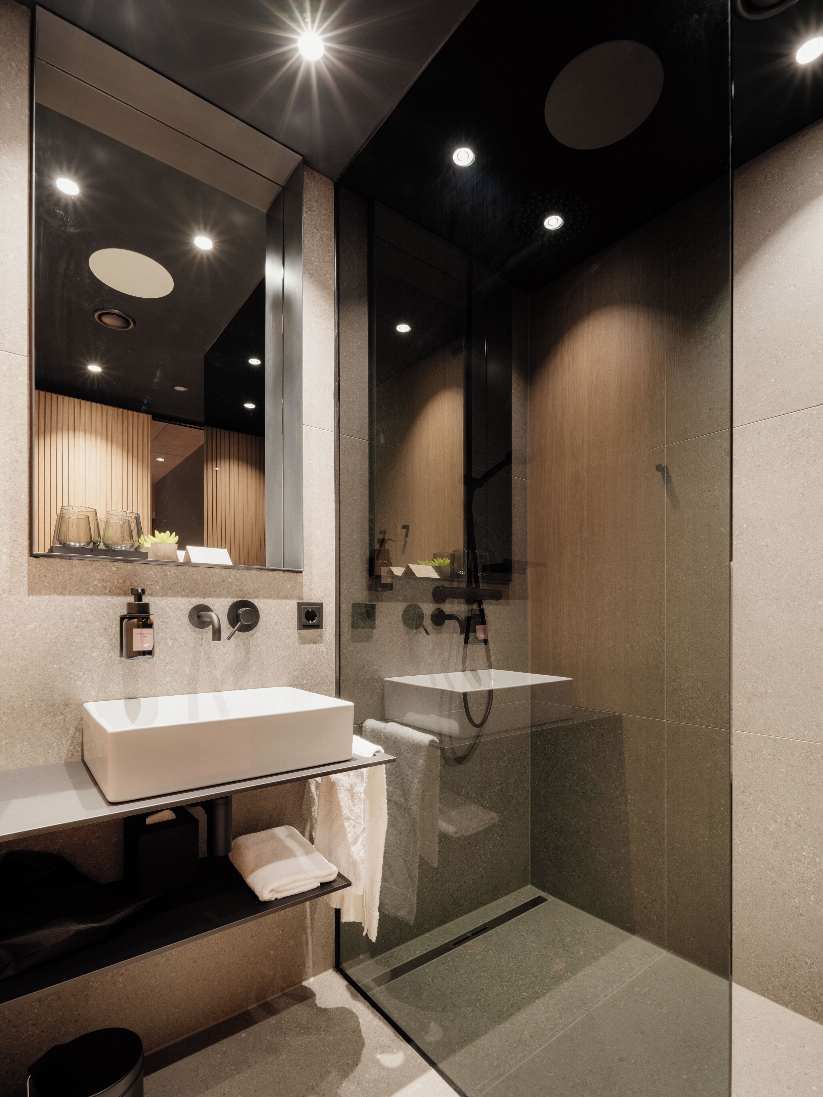 Un baño moderno con ducha de vidrio, un espejo grande y un tocador con lavamanos.