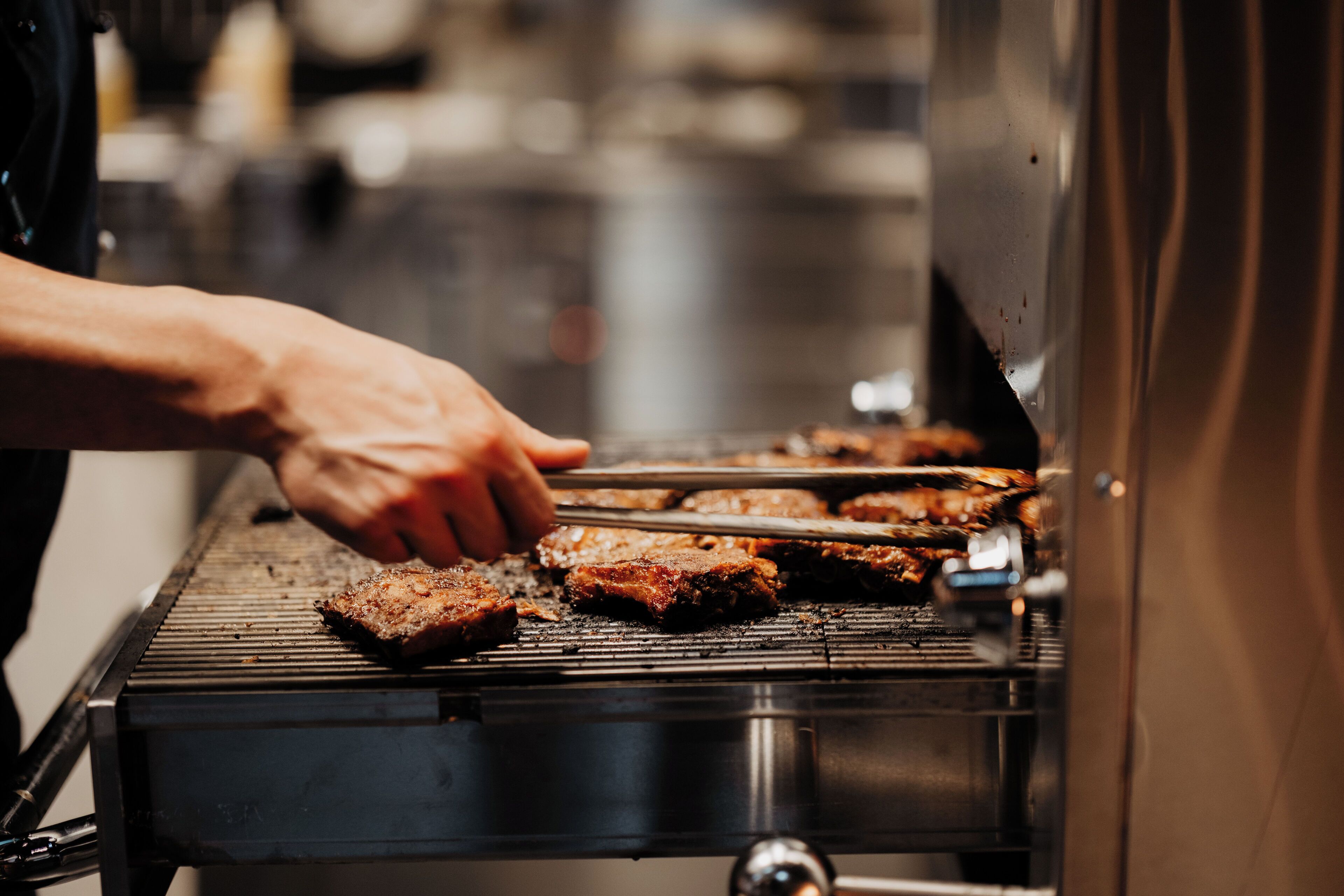 A person grilling meat on a barbecue.